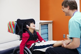 Ein Arzt überprüft bei einem Jungen mit cerebraler Bewegungsbehinderung die Bewegungen der Füsse.