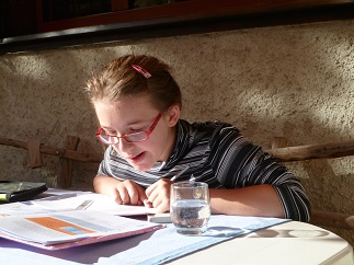 Ein Mädchen mit einer cerebralen Bewegungsbehinderung macht Schulaufgaben.